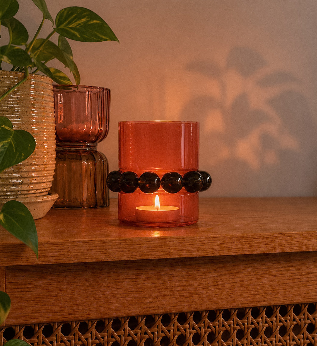 Shop our rust glass candle holder with dark beaded detail. A warm, retro home decor piece for shelves, tables and cosy styling.